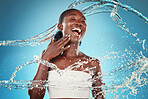 Water, splash and woman washing for hygiene and grooming on a blue studio background. Young black woman wash, cleanse and cleansing body and skin for bodycare, skincare and health or wellness 