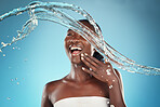 Happy, beauty and splash of water with black woman for shower, health and skincare. Wellness, spa and luxury with girl model for hydration, moisture and natural cosmetics in blue background studio 