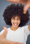 Comic, goofy and woman with hands for frame for marketing, creative and funny against a grey studio background. Happy, comedy and portrait of a girl sticking out tongue with a smile for a crazy photo
