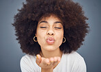 Kissing, love and romance with a black woman blowing a kiss in studio on a gray background for romantic affection. Beauty, lips and flirt with an attractive young female making a mouth gesture