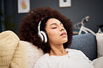 Music, relax and black woman on a sofa listening to radio, streaming or wellness podcast in a living room. Headphones, woman and rest on a couch with online audio track, meditation and playlist 