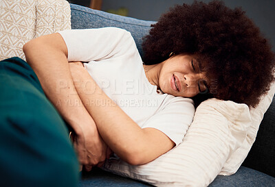 Buy stock photo Black woman, stomach on sofa with menstruation and pain holding abdomen in home living room. Woman, lounge and hurt, digestion or constipation on couch in house with period, cramps and belly ache