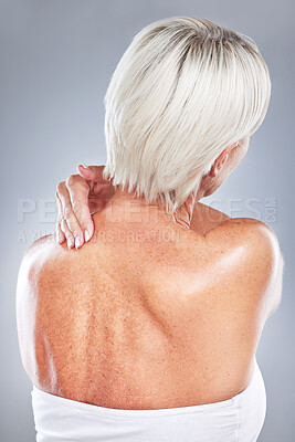Ache, pain and woman with neck injury on a grey studio background for body accident. In pain, back inflammation and physical strain of a woman anatomy from behind on a grey background.