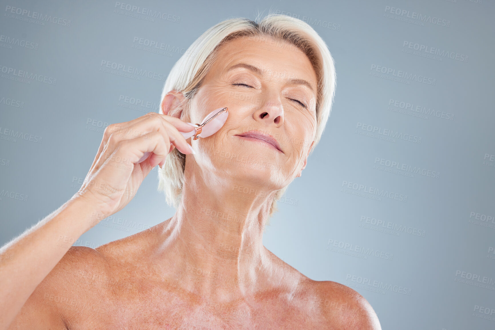 Buy stock photo Face, beauty and massage with a senior woman in studio on a gray background for skincare or wellness. Luxury, care and health with a mature female massaging her skin for natural antiaging treatment