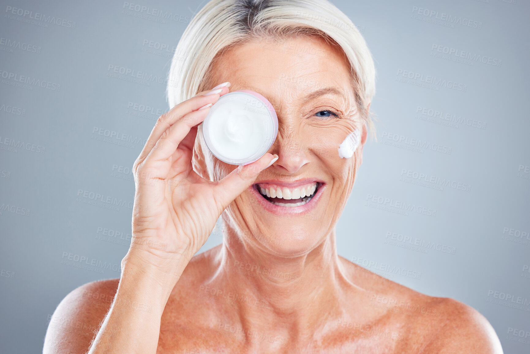 Buy stock photo Beauty, skincare and senior woman with face cream for moisturizing on a gray studio background. Smile, model and female with facial creme, lotion or cosmetics product for healthy skin or anti aging.