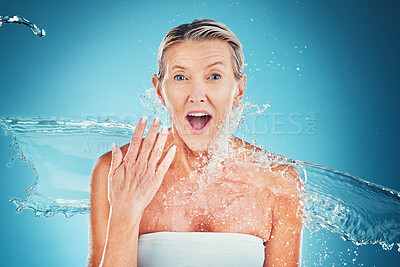Buy stock photo Beauty splash, senior woman and wow face in studio for cleaning, fresh and grooming on blue background. Skincare, water splash and elderly lady model shocked by water, hydration and moisture product