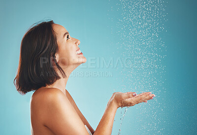 Buy stock photo Shower, woman and water splash in studio for cleaning, wellness and grooming, hair and body on blue background. Beauty splash, skincare and asian, girl and hygiene model happy, smile and relax wash