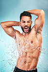 Muscular man, water splash and health for wellness, fitness and hygiene with blue studio background. Sing, athlete male and bodybuilder enjoy shower, wash clean or excited for body care after workout