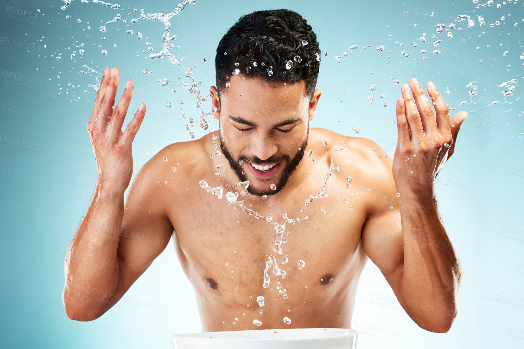 Buy stock photo Studio, water splash and face skincare of man isolated against a blue background. Health, hygiene and male model washing face, cleaning and grooming routine for wellness, beauty or facial freshness.