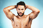 Health, shower and skincarre with man in studio for health, wellness and healthy lifestyle, body wet with water on blue background. Portrait of model in studio for self care and fitness motivation