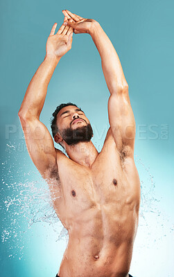 Buy stock photo Body, shower and water with a muscular man in studio on a blue background for wellness or hygiene. Bathroom, wet and fresh with a handsome young man washing for cleanliness or hygienic care