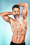 Body, water and shower with a muscle man in studio on a splash blue background for wellness or skincare. Bathroom, beauty and wet with a handsome young male washing his skin for hygiene cleanliness