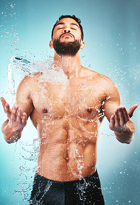 Buy stock photo Body, shower and water with a muscle man in studio on a blue background for hygiene, hydration or wellness. Bathroom, strong and cleanliness with a young male washing his skin for fresh care