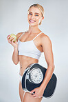 Body, diet and woman with scale and apple for health and wellness portrait, weight and healthy living against studio background. Nutrition, fruit and fiber, model smile for fitness and weightloss.
