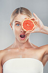 Wow studio portrait, woman with grapefruit for skincare wellness, beauty and face health by grey wall. Cosmetics model, surprise girl with fruit for healthy facial skin or vitamin c by background