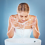 Woman, water or washing face in grooming skincare on blue background studio from sink or basin. Beauty model, wet and facial cleaning with water splash for hygiene maintenance, healthcare or wellness