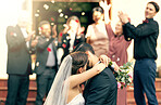 Bride, groom and kiss in wedding celebration with applause from family, friends or guests at the church indoors. Man and woman kissing, hugging or embracing marriage in romance for happy relationship