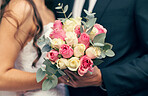 Flowers, wedding and love with a bouquet in the hands of a bride and groom on their marriage day closeup. Rose, married and celebration event with a floral arrangement in hand during a ceremony