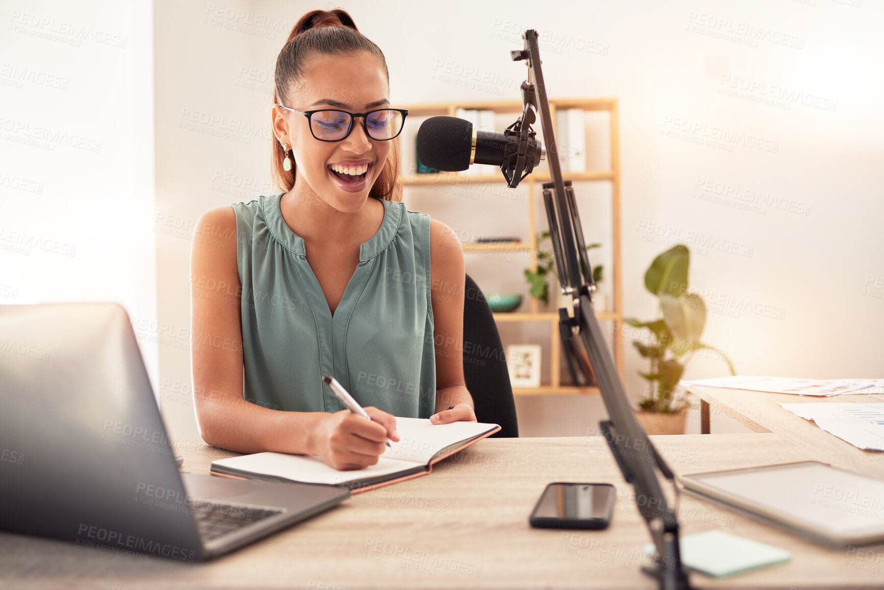 Buy stock photo Podcast microphone, laptop and woman writing in notebook for ideas, research or information. Influencer, presenter or journalist planning blog for live streaming, radio talk show or online broadcast.