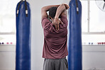 Boxer stretch, black man and athlete at a gym stretching arms before training and sports. Fitness, exercise and boxing health of a male fighter doing a back muscle workout for martial arts in a dojo 