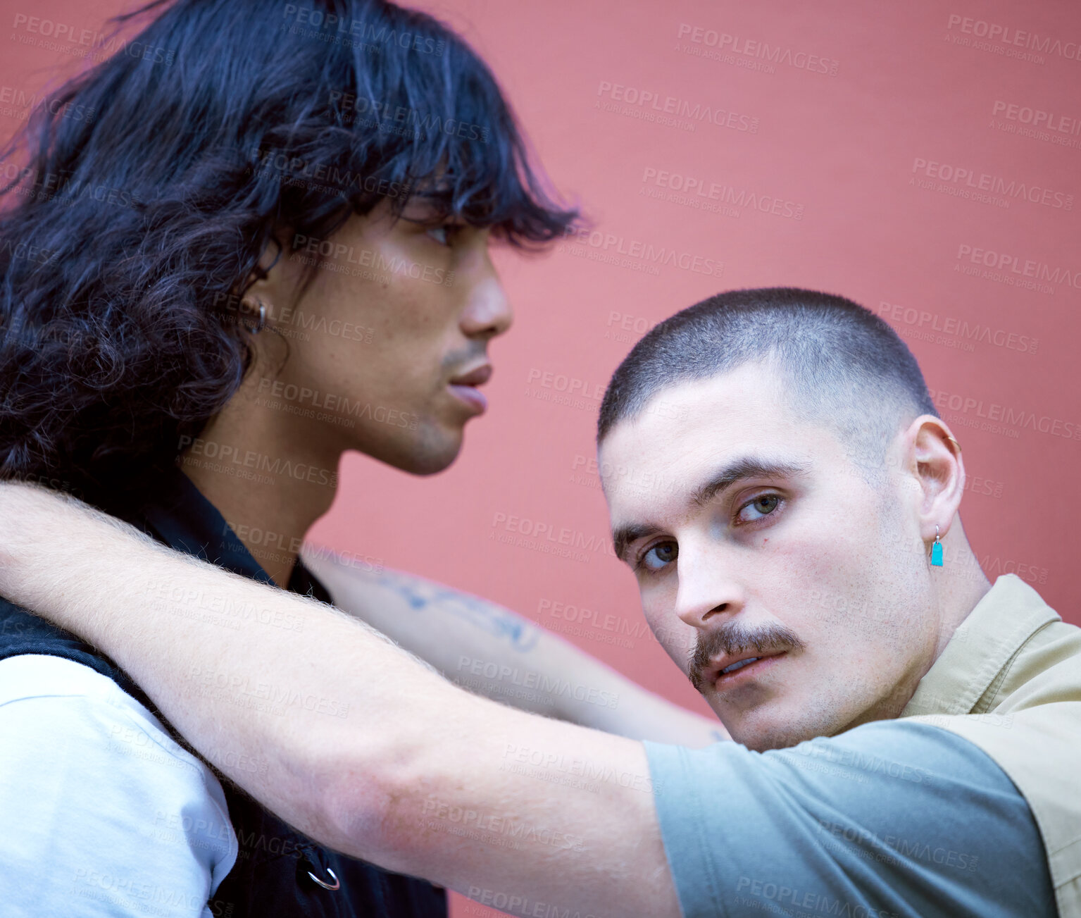 Buy stock photo Love, freedom and lgbtq couple relax, embrace and bond against a wall in a city, proud and content together. Gay, men and portrait of diverse lovers embracing in a red background, attitude and cool