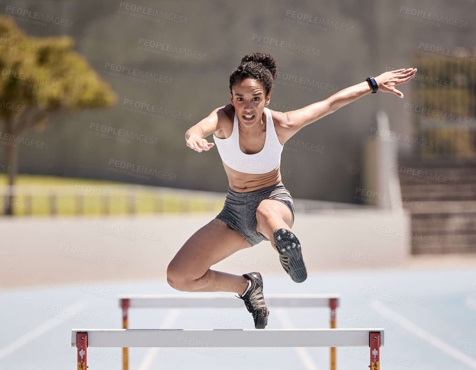 Buy stock photo Jump, athlete and hurdle black woman in sports race, competition or training at stadium with energy, power and body challenge. Fast, speed and runner at an arena course or field for workout exercise