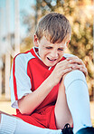 Soccer, children and knee injury with a boy hurt on a sports field during a competitive game or match. Fitness, football and pain with a kid injured on a grass pitch while playing a sport outdoor
