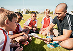 Soccer, football coach with team talk and strategy with tactics for winning game sitting on grass training field. Children athletes, teamwork and motivation to win youth competition match championship