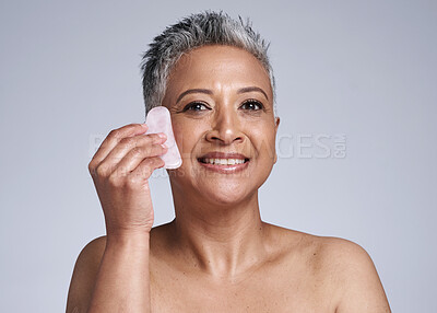 Buy stock photo Elderly, woman and portrait of massage with gua sha stone for wellness, circulation and beauty. Skincare model massaging face with natural crystal for facial treatment in gray studio mockup.