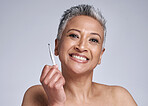 Beauty, tweezer and portrait of a senior woman grooming her facial hair for skincare in a studio. Cosmetic, self care and happy elderly lady with a smile for clear skin isolated by a gray background.