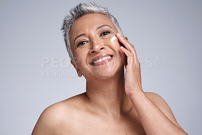 Buy stock photo Face, skincare and beauty with a mature woman using moisturizer for antiaging treatment in studio on a gray background. Wellness, facial and portrait with a senior female inside for dermatology care