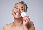 Woman, elderly and beauty portrait with cotton pad for cosmetic, makeup and product removal on face. Cleaning, facial and skincare cleansing model happy with mature skin in mock up gray studio.