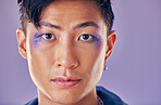Punk, creative and man with makeup on face for metal, rock and trippy identity against a purple studio background. Expression, funky and portrait of Asian model or person in a band with mockup space