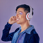 Music, makeup and cyberpunk with an asian man model in studio on a purple background for lgbt freedom. Future, happy and fashion with a handsome young androgynous male streaming or listening to audio