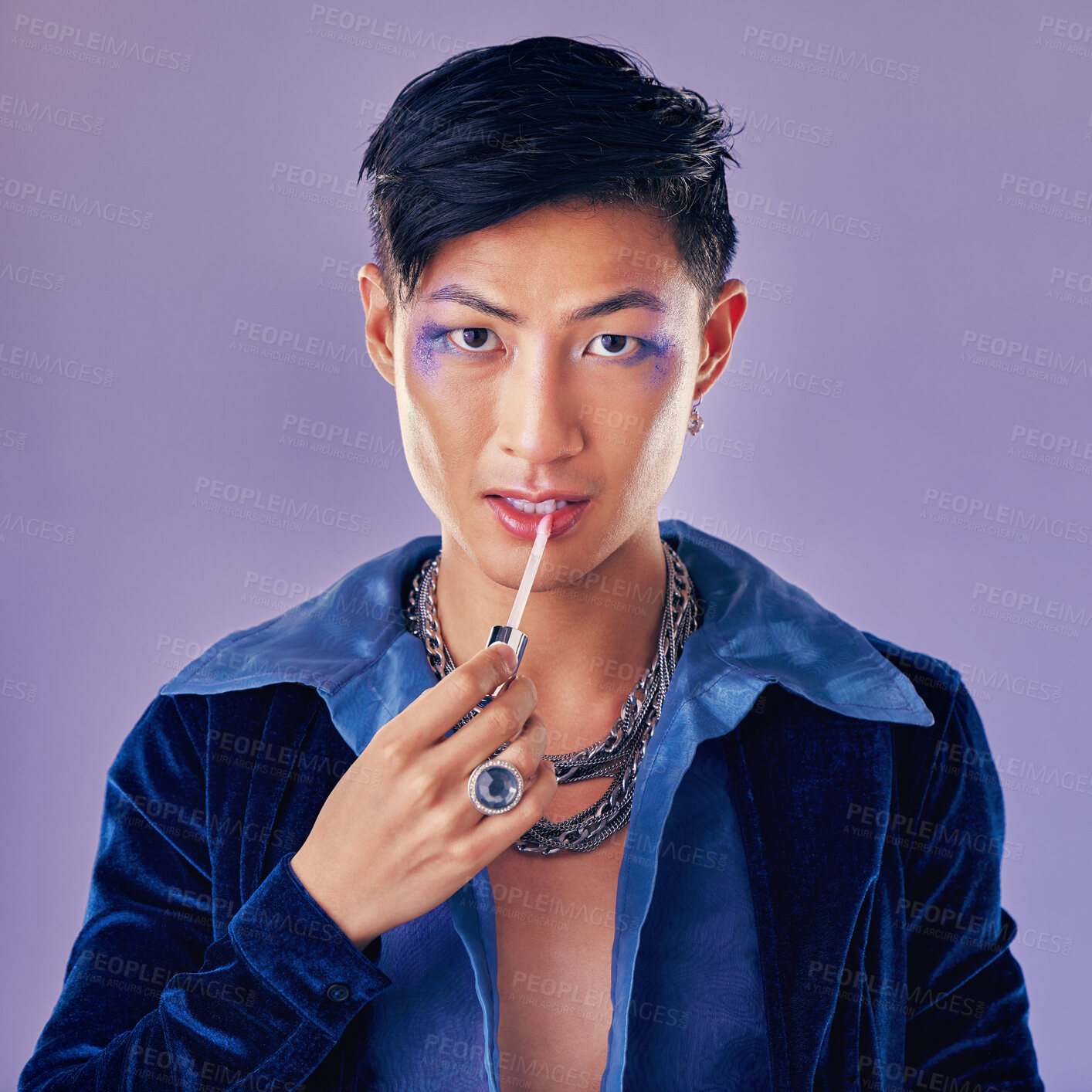 Buy stock photo Fashion, beauty and makeup with a man model in studio on a purple background applying red lipstick. Face, portrait and cosmetics with a young asian male indoors to promote a cosmetic product