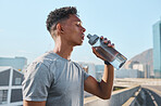 City, fitness and man drinking water after running in street, thirsty after workout in summer heat. Sun, exercise run and sweat, urban black man with healthy lifestyle and water bottle relax on road