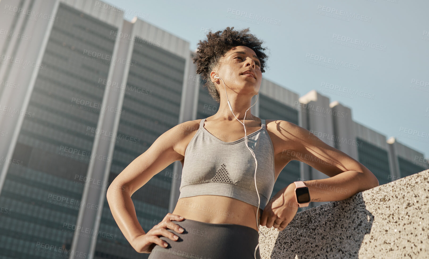 Buy stock photo Black woman, city fitness and music earphones for sports motivation, exercise and workout in urban town from below. Focus, strong and healthy athlete listening to audio outdoors for wellness training