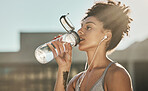 Runner, fitness and woman drinking water with online audio podcast for exercise workout or training in city. Black woman, streaming music and healthy cardio or hydration after sports run in outdoors 