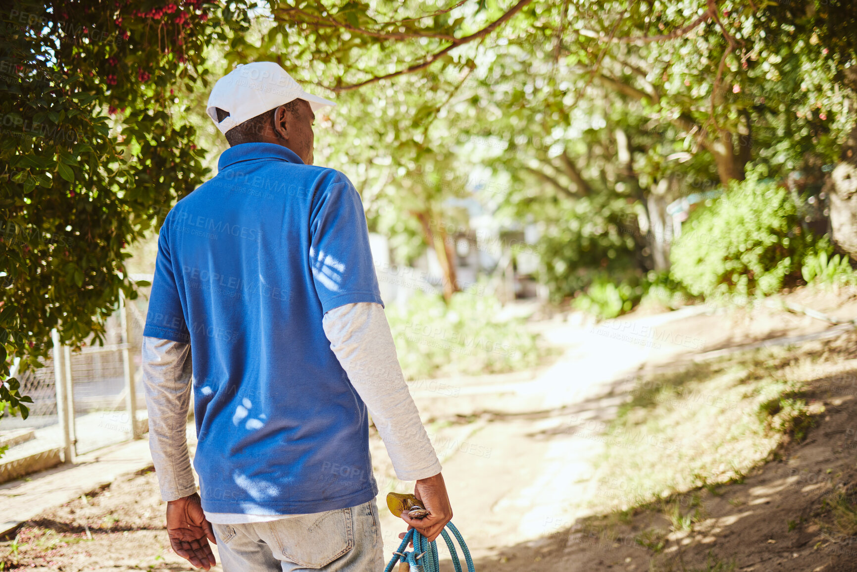 Buy stock photo Outdoor animal shelter, cleaning and worker with hose walking in nature to clean for volunteer work. Community, charity and black man working at rescue center for dogs, animals and adoption of pets