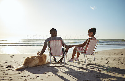 Buy stock photo Black couple, dog and sunset beach while on chair to relax on vacation holding hands for love, care and trust by ocean for quality time. Pet with man and woman in healthy marriage on holiday by sea