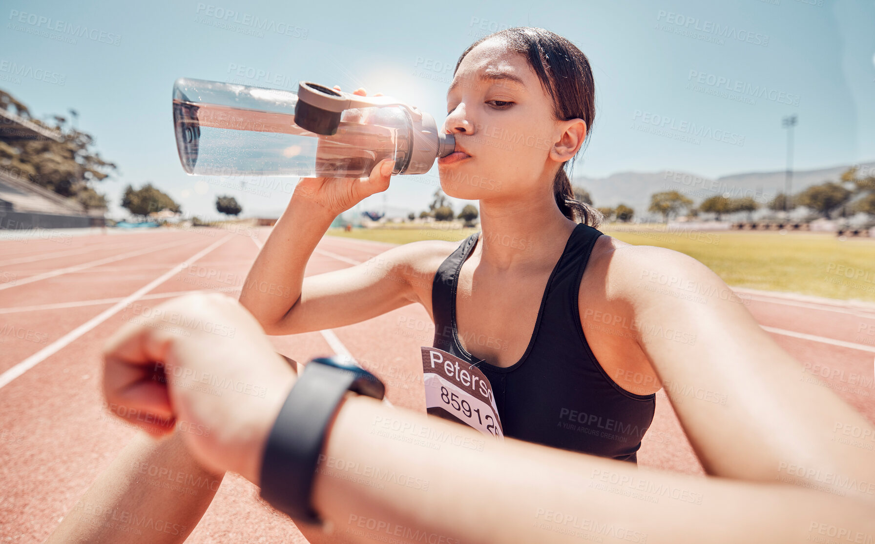 Buy stock photo Drinking water, time and running with a sports woman checking her watch during a workout on track. Fitness, exercise and hydration with a female athlete tracking her progress during cardio training