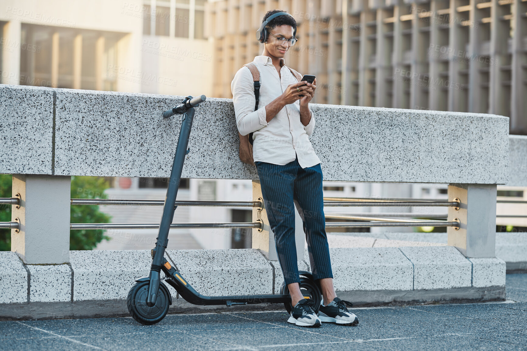Buy stock photo Phone, music and electric scooter with a business black man streaming audio during his commute into work. Mobile, headphones and transport with a male employee typing a text message in an urban town