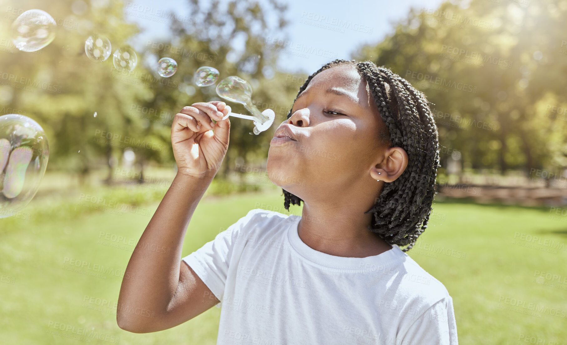 Buy stock photo Park, child and black girl blowing bubbles enjoying fun time alone outdoors, joy and childhood development. Happy, freedom and kid learning and playing with soap bubble toy or wand and relax on grass