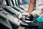 Cleaning, treadmill and sanitizing equipment in gym for bacteria, germs or protection from covid. Disinfection, sanitizer and closeup of cleaner wiping running machine for fitness in sports center.