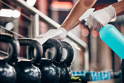 Buy stock photo Kettlebell, cleaning service and hands cleaning at a gym with liquid soap in spray bottle with cloth in gloves. Janitor or cleaner wipes dirty bacteria on dusty weights or fitness training equipment