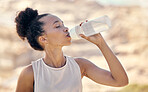 Fitness, wellness and black woman drinking water after exercise, training and workout in nature, park and outdoors. Hydration, health and thirsty female athlete drink from water bottle after running