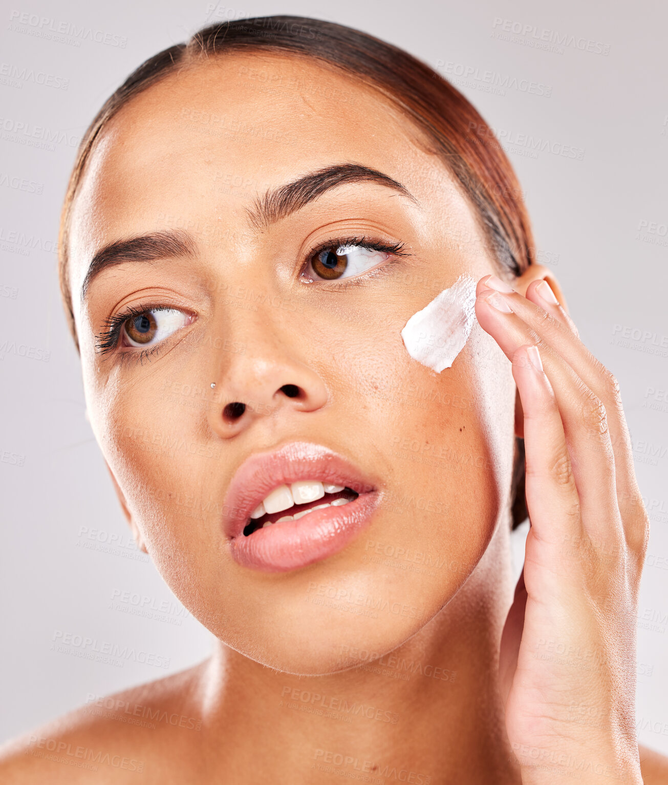 Buy stock photo Face, beauty and skincare with a model black woman using moisturizer on her skin in studio on a gray background. Wellness, cosmetics and cream with a female posing to promote antiaging treatment