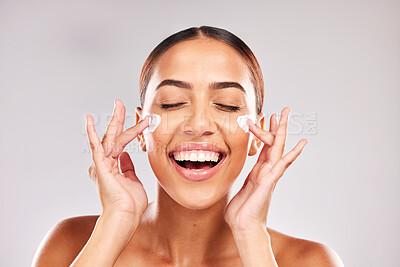Buy stock photo Skincare, beauty and woman with face cream in a studio doing a natural face and skin routine. Cosmetic, wellness and happy girl model with facial lotion, spf or sunscreen isolated by gray background.