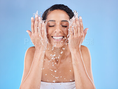 Buy stock photo Skincare, water and woman washing face for clean, healthy and natural wellness against a blue studio background. Beauty, cleaning and happy model with splash for facial satisfaction and routine