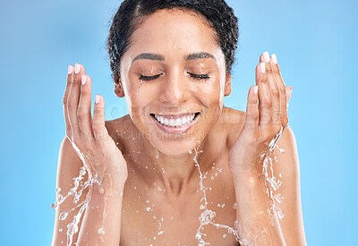 Buy stock photo Water splash black woman cleaning face on blue background for health, beauty and skin care morning routine. Skincare, luxury cosmetics and happy woman with smile washing makeup with water in studio.